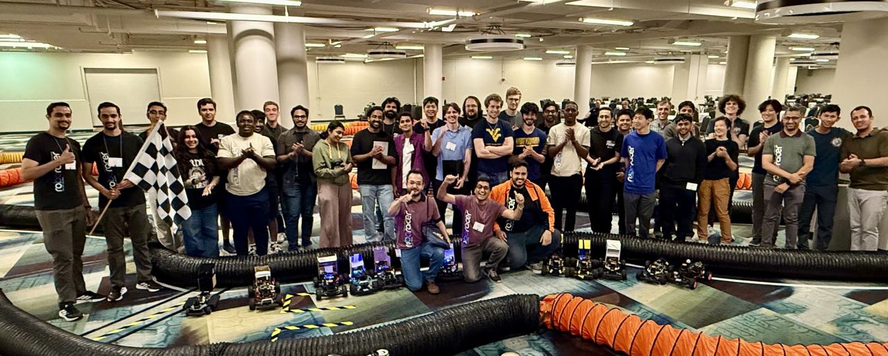 Roboracer teams and organizers beside their cars at IV 2026 in Detroit.